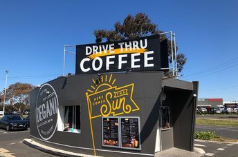 Modern Cafe Design Blends Dark Tones, Vibrant Signage, and Inviting Atmosphere for a Convenient Drive-Thru Experience