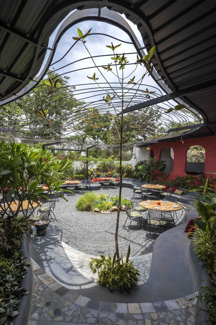 Inviting Cafe Design with Lush Greenery, Flowing Roof, and Flexible Seating for a Relaxed Atmosphere