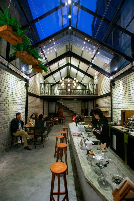 Stylish cafe boasts high ceilings, natural light, rustic charm, and a warm atmosphere for an inviting coffee experience