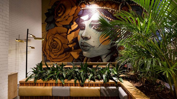 Vibrant Cafe Design with Striking Mural, Lush Greenery, and Inviting Ambiance