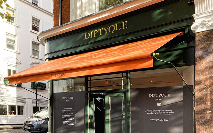 Sophisticated Cafe Design Blends Deep Green Facade, Elegant Gold Lettering, and Striking Orange Awning for Inviting Atmosphere