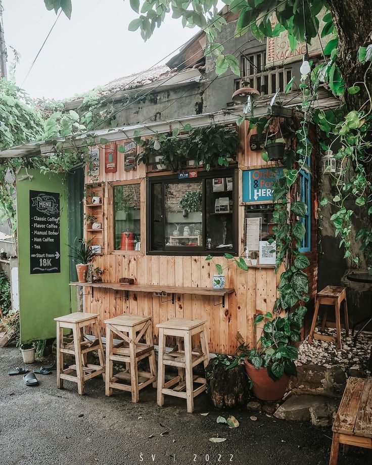 Charming Rustic Cafe: Inviting Wood Facade and Cozy Outdoor Seating Amidst Lush Greenery