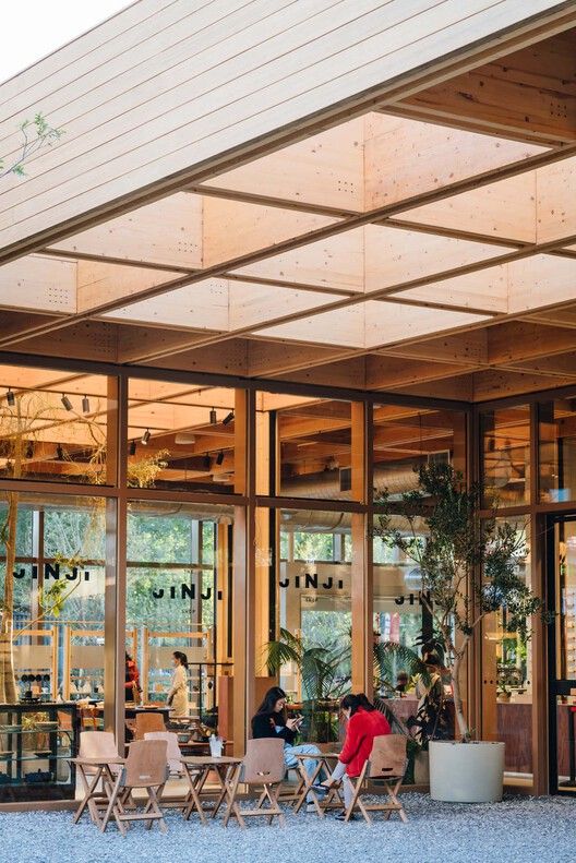 Contemporary Cafe Design: Embracing Glass, Natural Wood, and Greenery for a Warm, Inviting Atmosphere