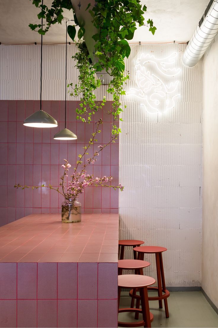 Modern Cafe Design: Inviting Atmosphere with Pink Tiled Counter and Lush Greenery