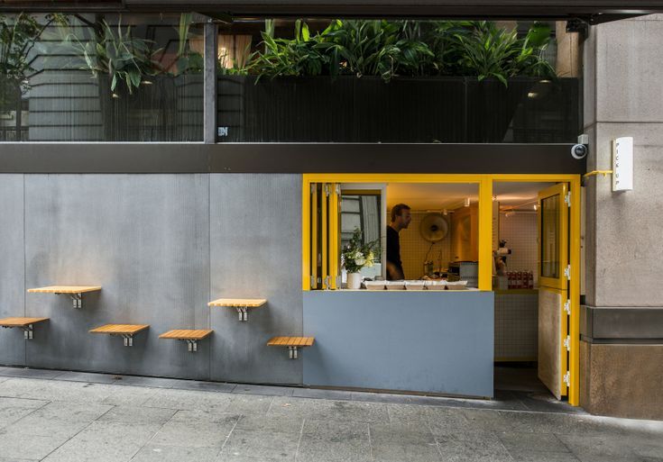 Sleek Modern Cafe Design: Concrete, Yellow Accents, and Inviting Greenery