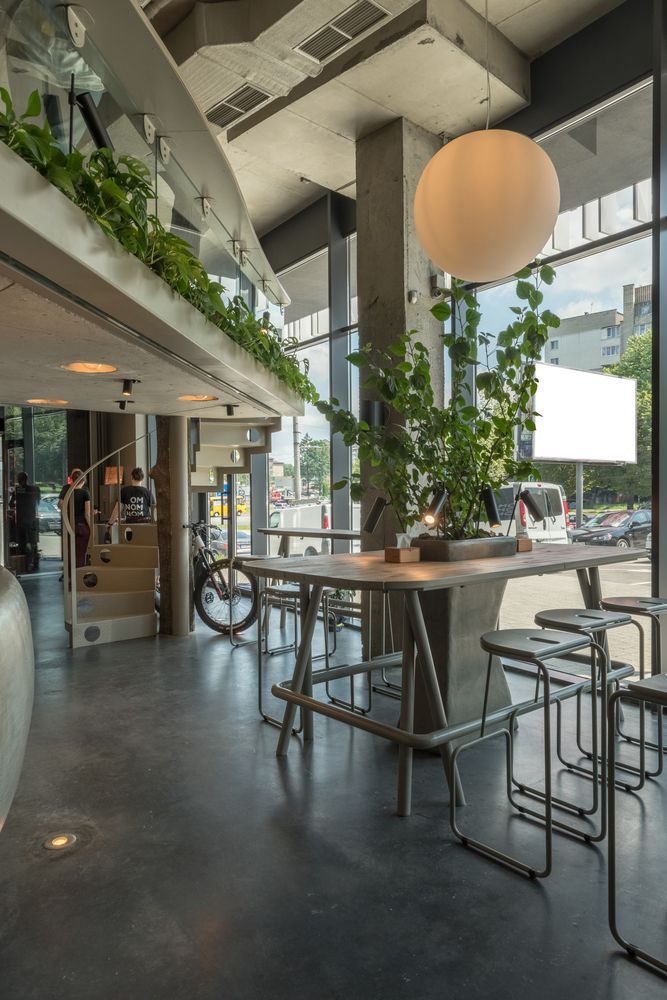 Modern Open Cafe Design with Concrete Elements and Inviting Greenery