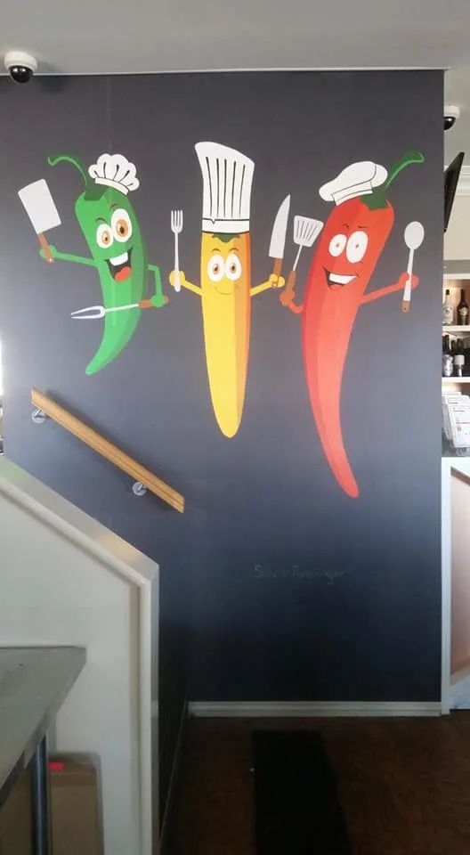 Vibrant Mural of Animated Chili Peppers Creates a Playful and Inviting Cafe Atmosphere