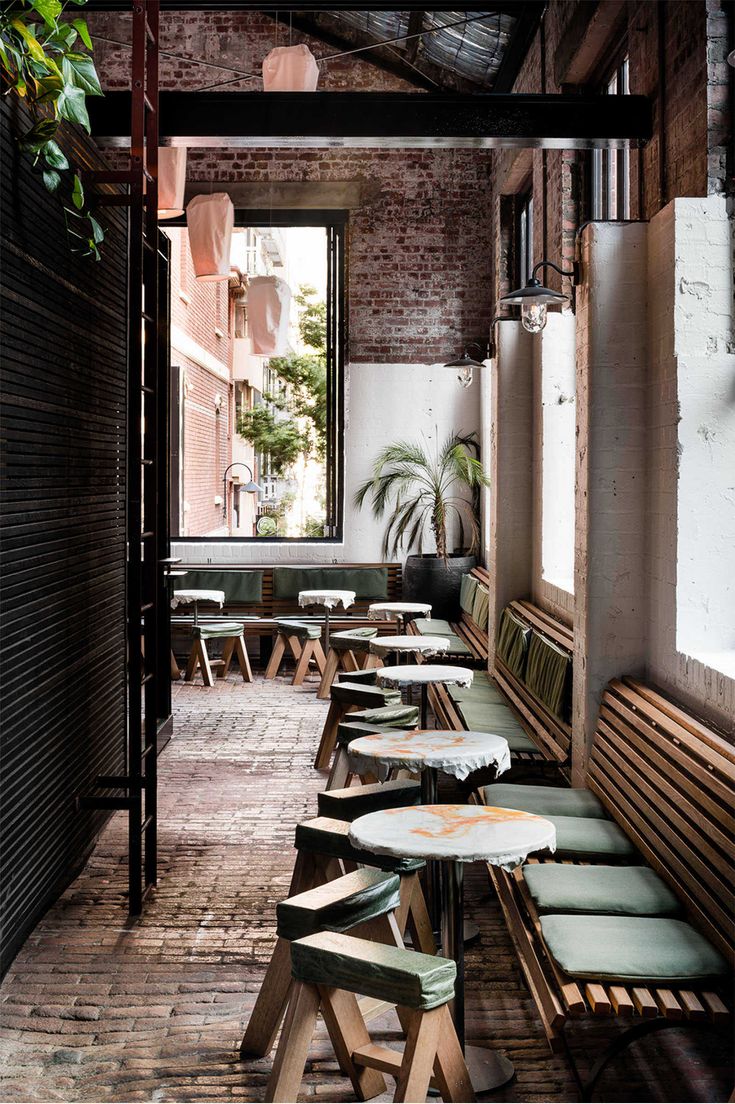 Inviting Modern Cafe Design with Exposed Brick, Natural Light, and Cozy Greenery