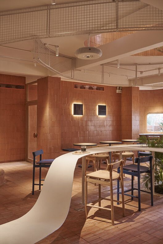 Warm and Inviting Cafe Design with Terracotta Walls, Flowing White Table, and Playful Modern Seating