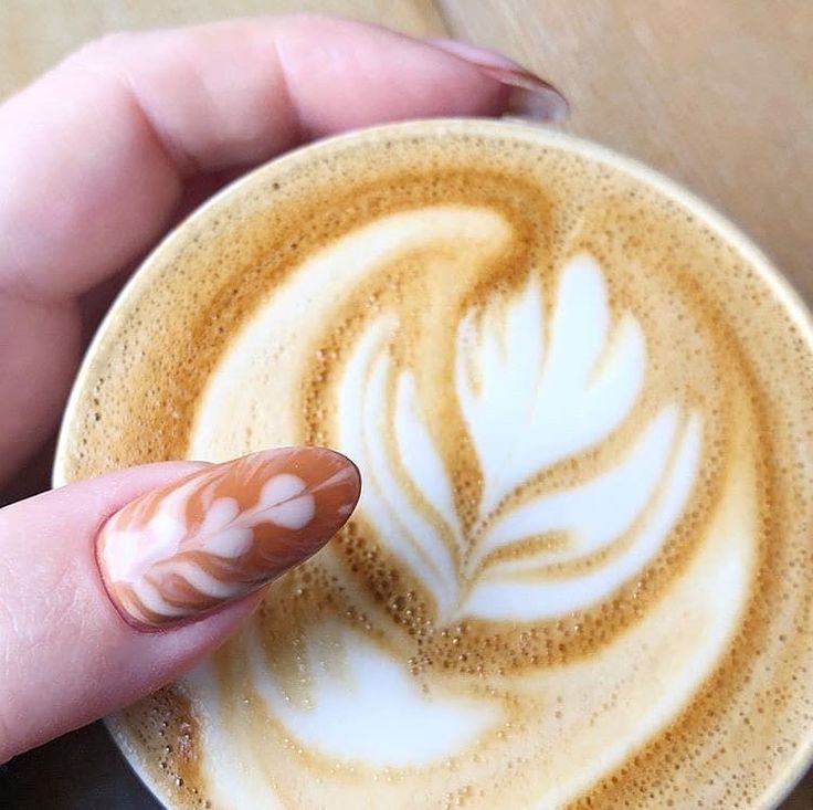 Artful Latte and Elegantly Adorned Hand in a Cozy Cafe Setting