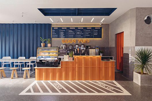 Modern Cafe Design: A Welcoming Space with Striking Wooden Counter and Playful Flooring