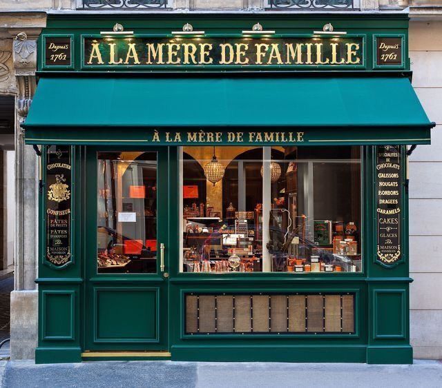 Charming Parisian Cafe with Elegant Green Facade and Golden Accents Invites Passersby