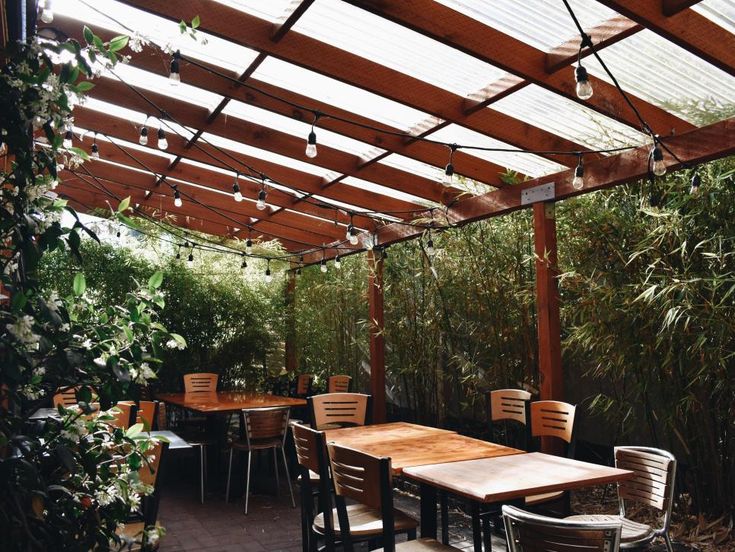 Charming Cafe Design: Inviting Outdoor Space with Wooden Pergola, Cozy Ambiance, and Lush Greenery for Relaxation and Socializing