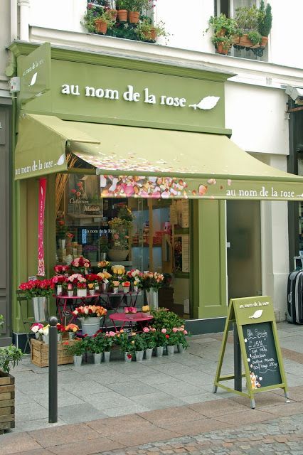 Charming Cafe with Inviting Green Facade and Floral Accents Creates a Relaxing Garden Atmosphere