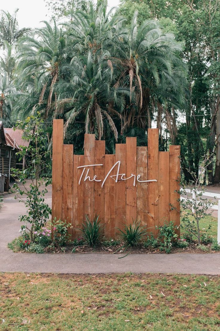 Serene Cafe Entrance Featuring Rustic Wooden Wall and Lush Greenery for a Modern-Earthy Ambiance