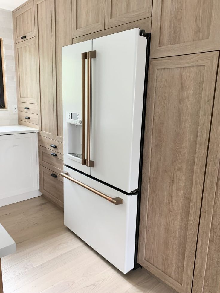 Modern Kitchen Design: Sleek White Refrigerator with Gold Accents and Warm Wood Cabinetry