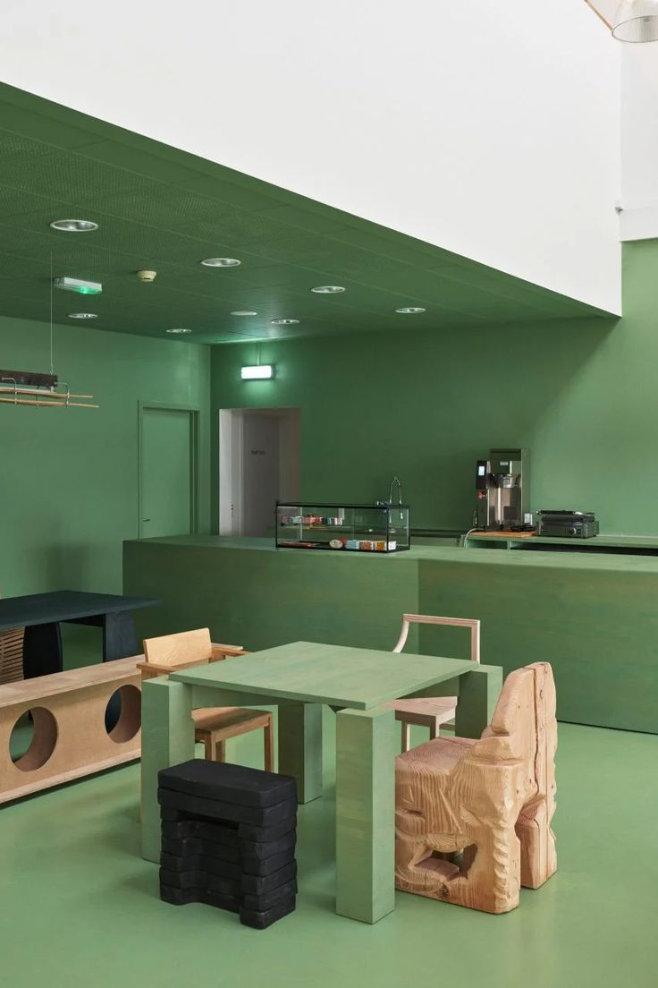 Inviting Cafe Design Blends Cohesive Green Palette with Minimalist Furnishings for a Vibrant Atmosphere