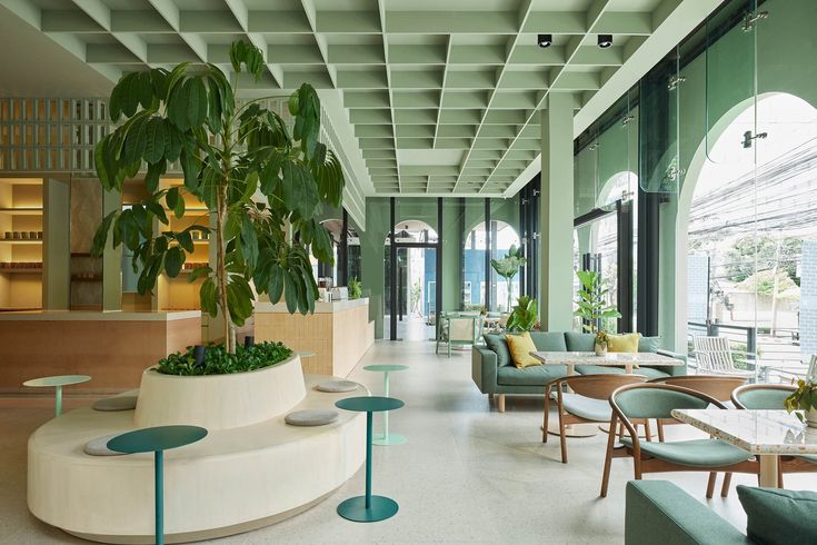 Modern Cafe Design Blends Airy Aesthetics with Inviting Green Palette and Comfortable Social Spaces