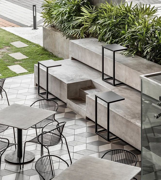 Modern Cafe Design: Sleek Outdoor Seating with Tiered Concrete Platforms and Industrial Aesthetics