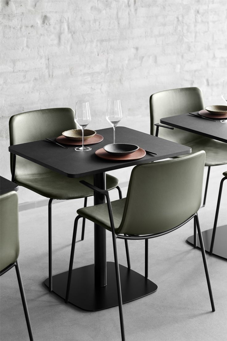 Modern Minimalist Cafe Design: A Light and Airy Ambiance with Sleek Black Topped Tables and Warm Green Upholstered Chairs