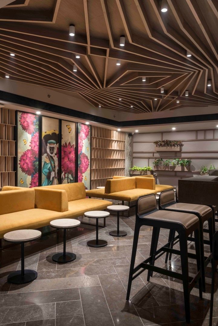 Contemporary Cafe Design: Striking Angular Ceiling, Modern Seating, and Vibrant Art Create a Warm, Inviting Ambiance