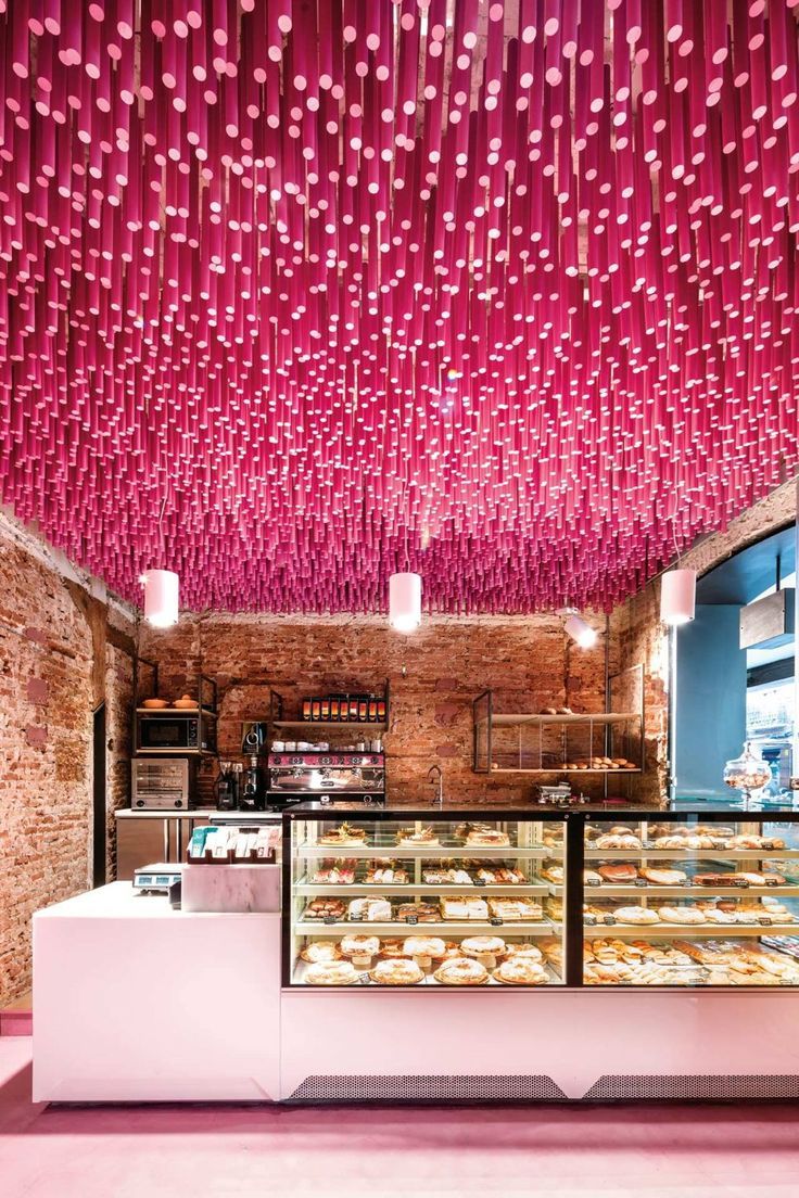 Vibrant Pink Ceiling and Textured Brick Walls Create a Dynamic and Inviting Cafe Atmosphere