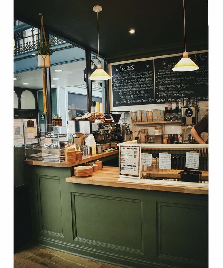 Cozy Cafe Design: Warm Green Accents, Natural Wood Counter, and Inviting Ambiance for Community Gatherings