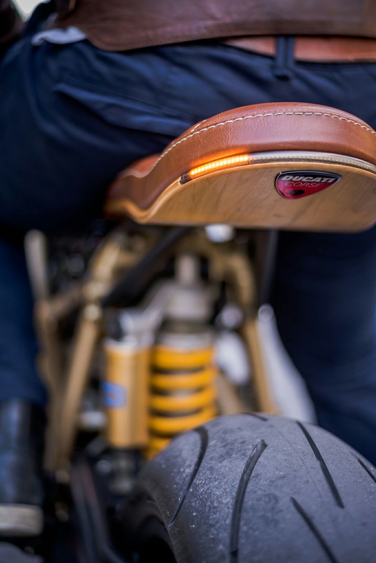 Stylish Motorcycle Rear: Brown Leather Seat with Wood Elements and Vibrant Shock Absorber