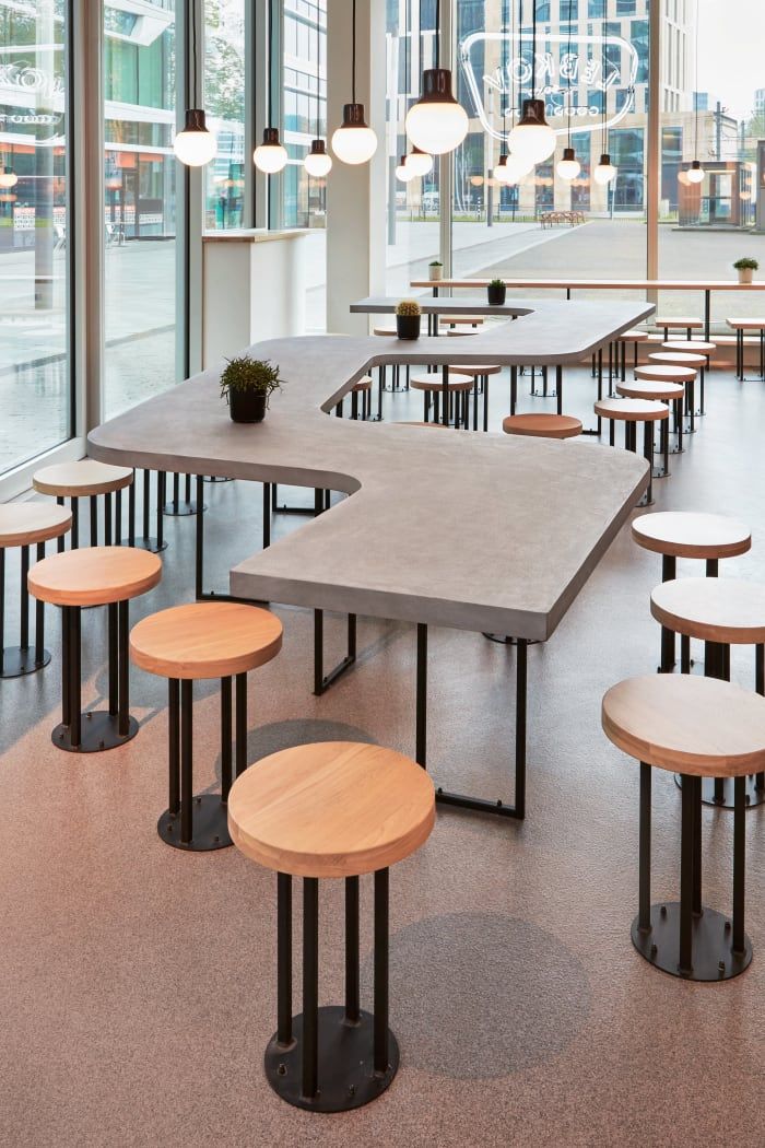 Modern Cafe Design: Organic Concrete Table, Stylish Stools, and Inviting Ambiance