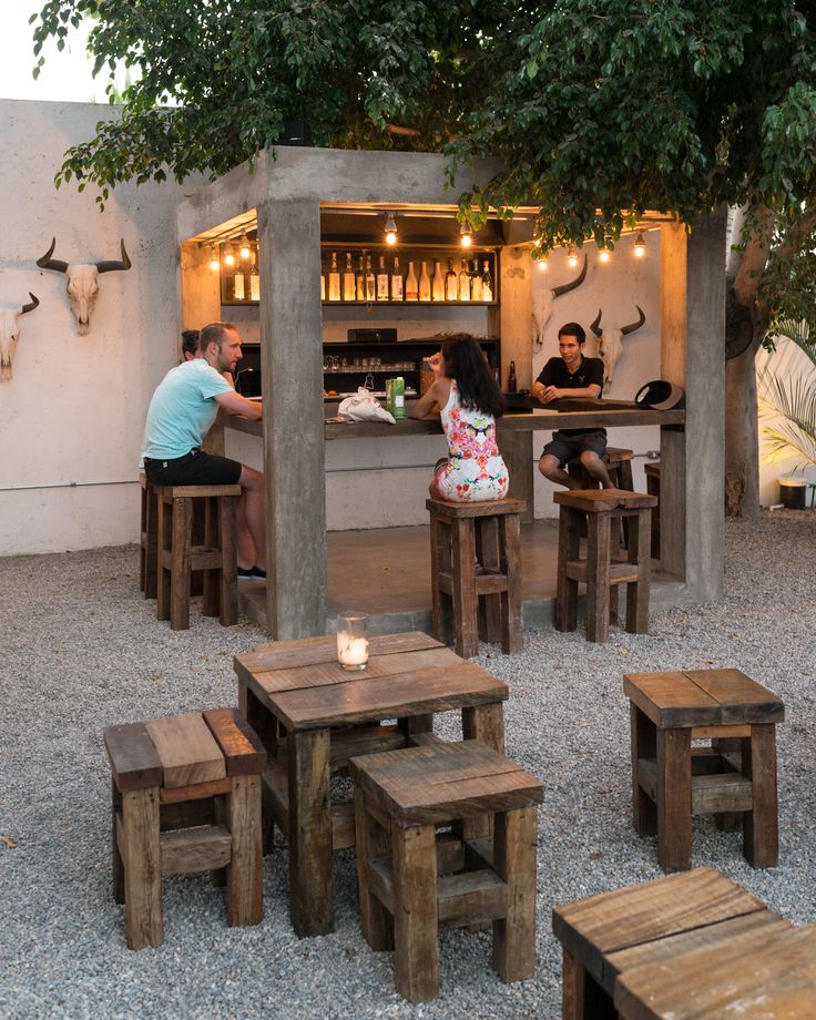 Rustic Outdoor Cafe Design: Inviting Space with Concrete Pillars, Wooden Seating, and Cozy Ambiance