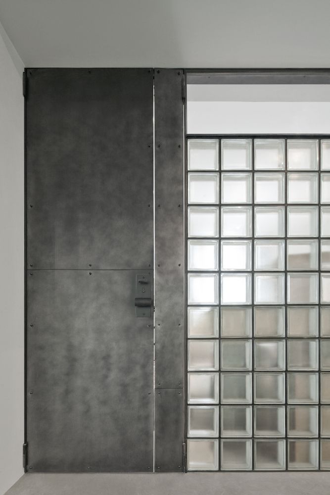 Modern Cafe Design: A Striking Contrast of Sleek Metal Door and Textured Glass Block Wall