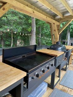 Stylish Outdoor Cooking Space with Sleek Appliances and Warm Wooden Countertops Amidst Greenery