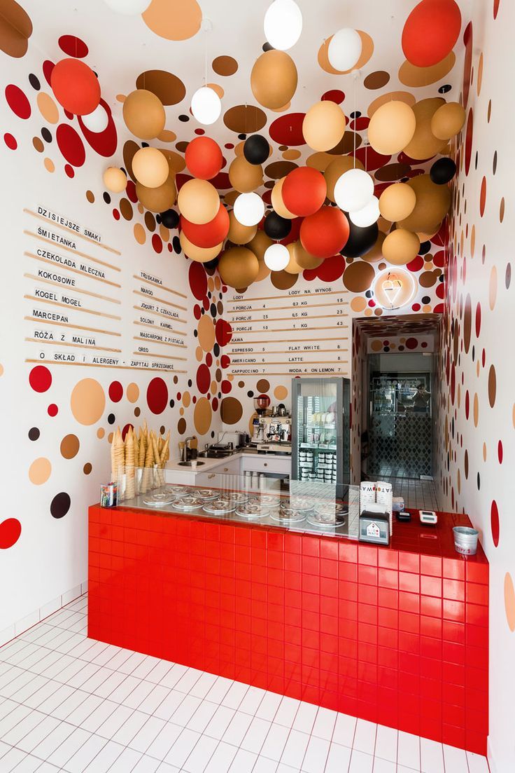 Vibrant Cafe Design: Bold Polka Dots, Striking Red Counter, and Whimsical Hanging Orbs